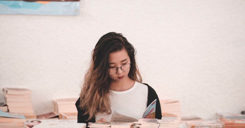 Asian woman engrossed in reading, surrounded by books in an indoor setting.