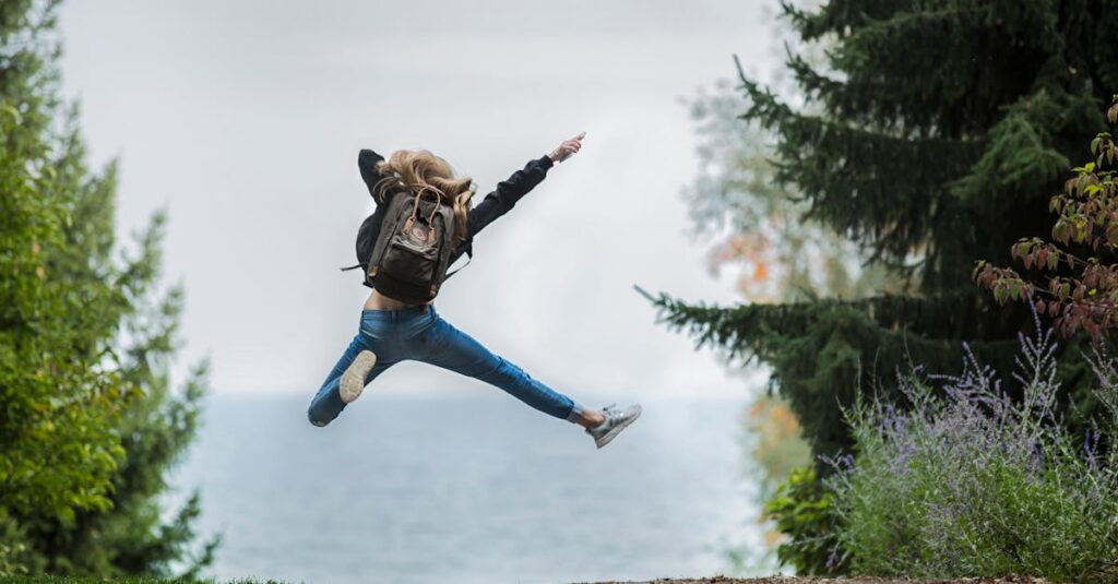 Energetic woman leaping in outdoor forest setting with lake view, showcasing freedom and joy.